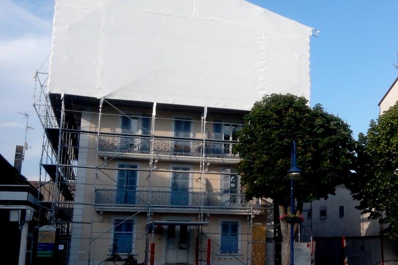 Edifício envolvido em andaime e tela de confinamento durante a remoção de amianto